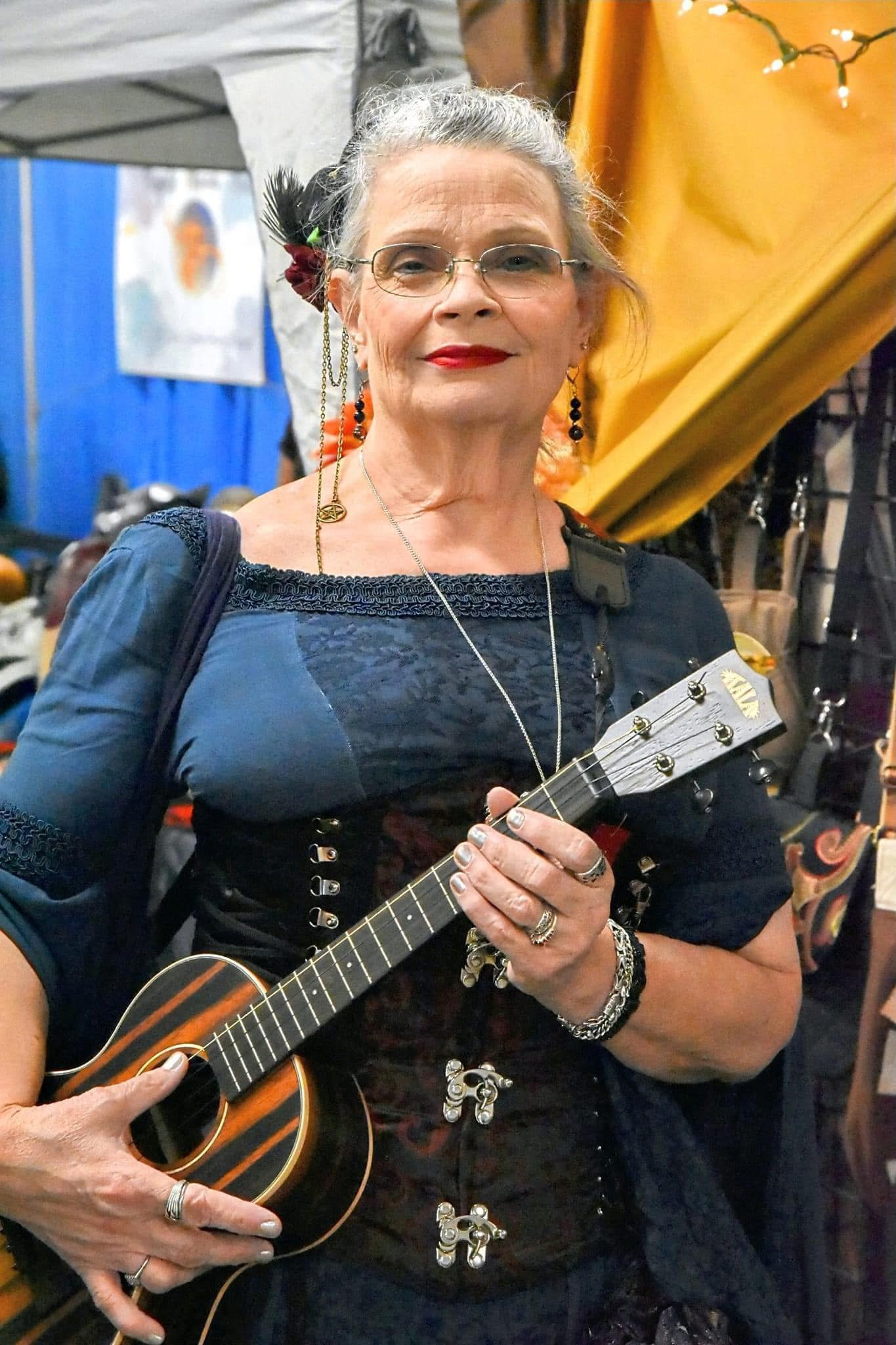 Ukulele performer holding a striped wooden ukulele at a Renaissance faire